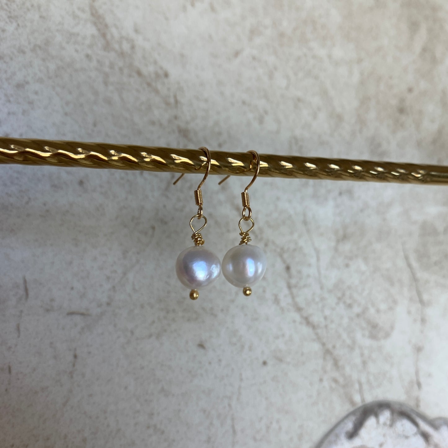 Close-up of handcrafted gold and pearl drop earrings showcasing lustrous, natural freshwater pearls.