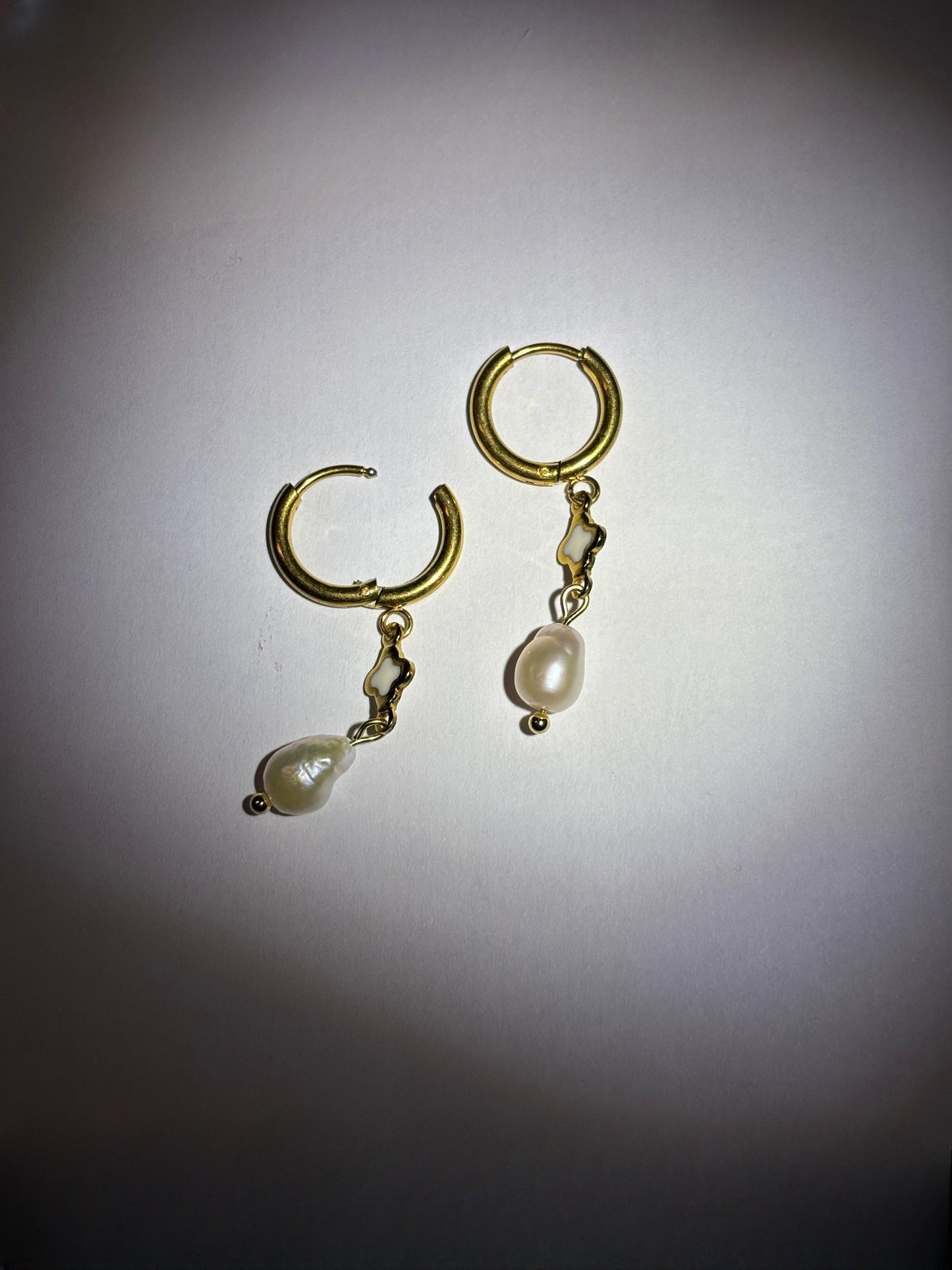 Asymmetrical baroque pearl earrings with gold-tone hoops and delicate cutout charm.