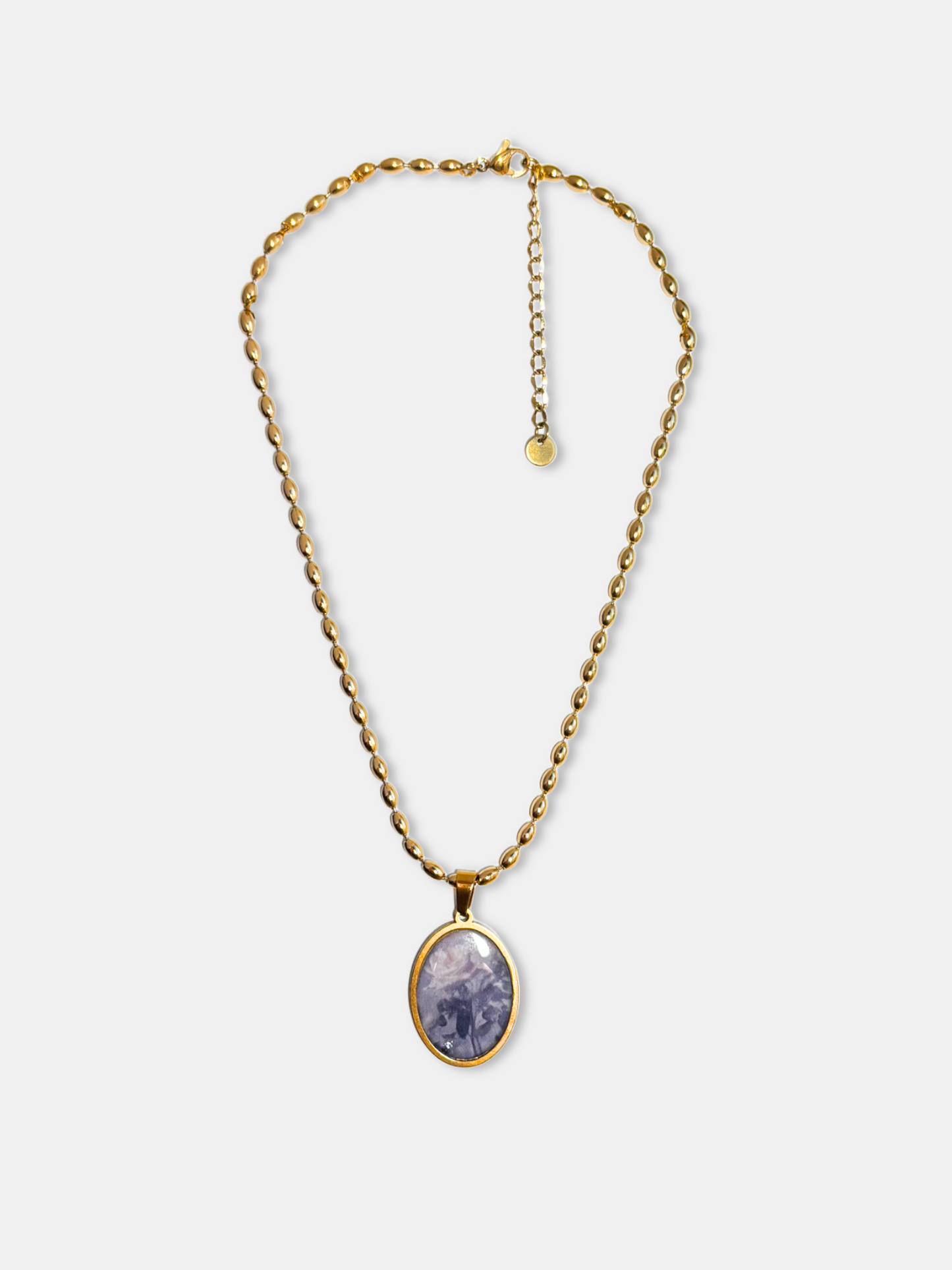 Romantic gold necklace with oval pendant, featuring a faded rose artwork on white background.