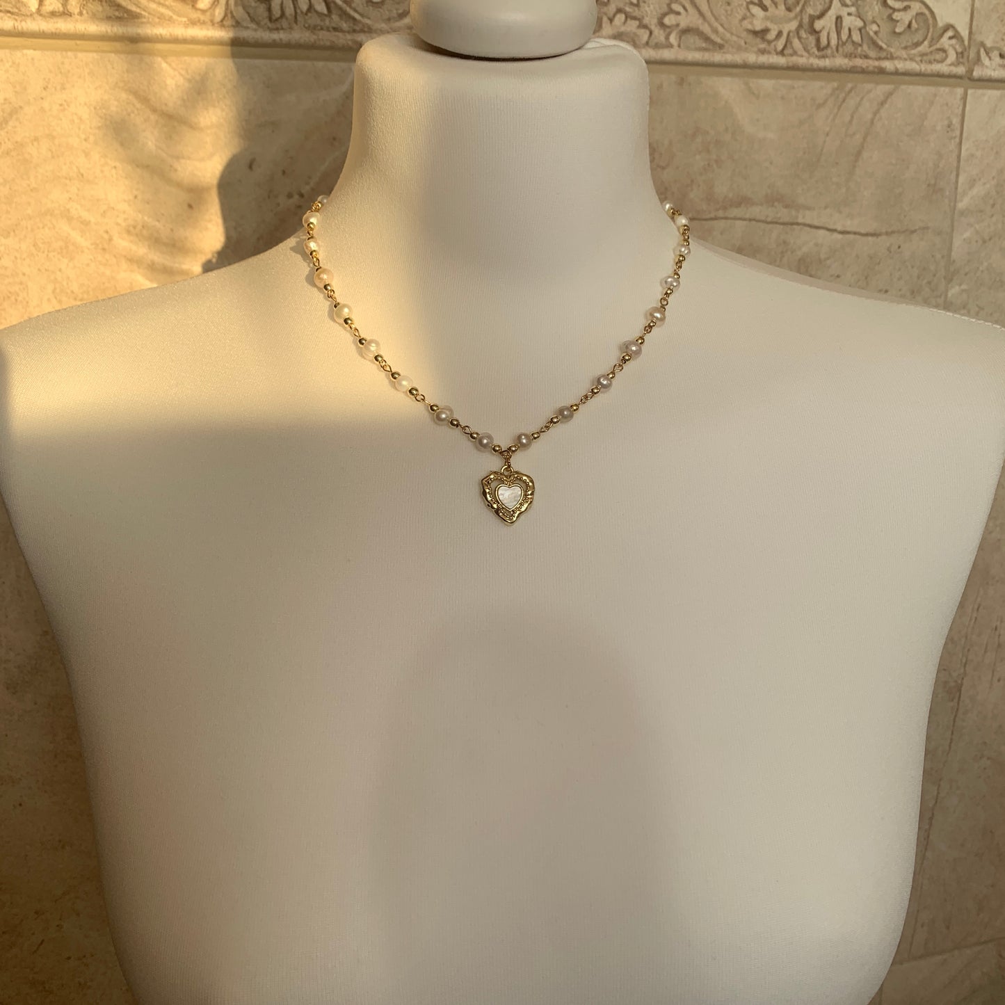 Feminine vintage-inspired pearl necklace with a gold heart charm, featuring genuine baroque pearls.