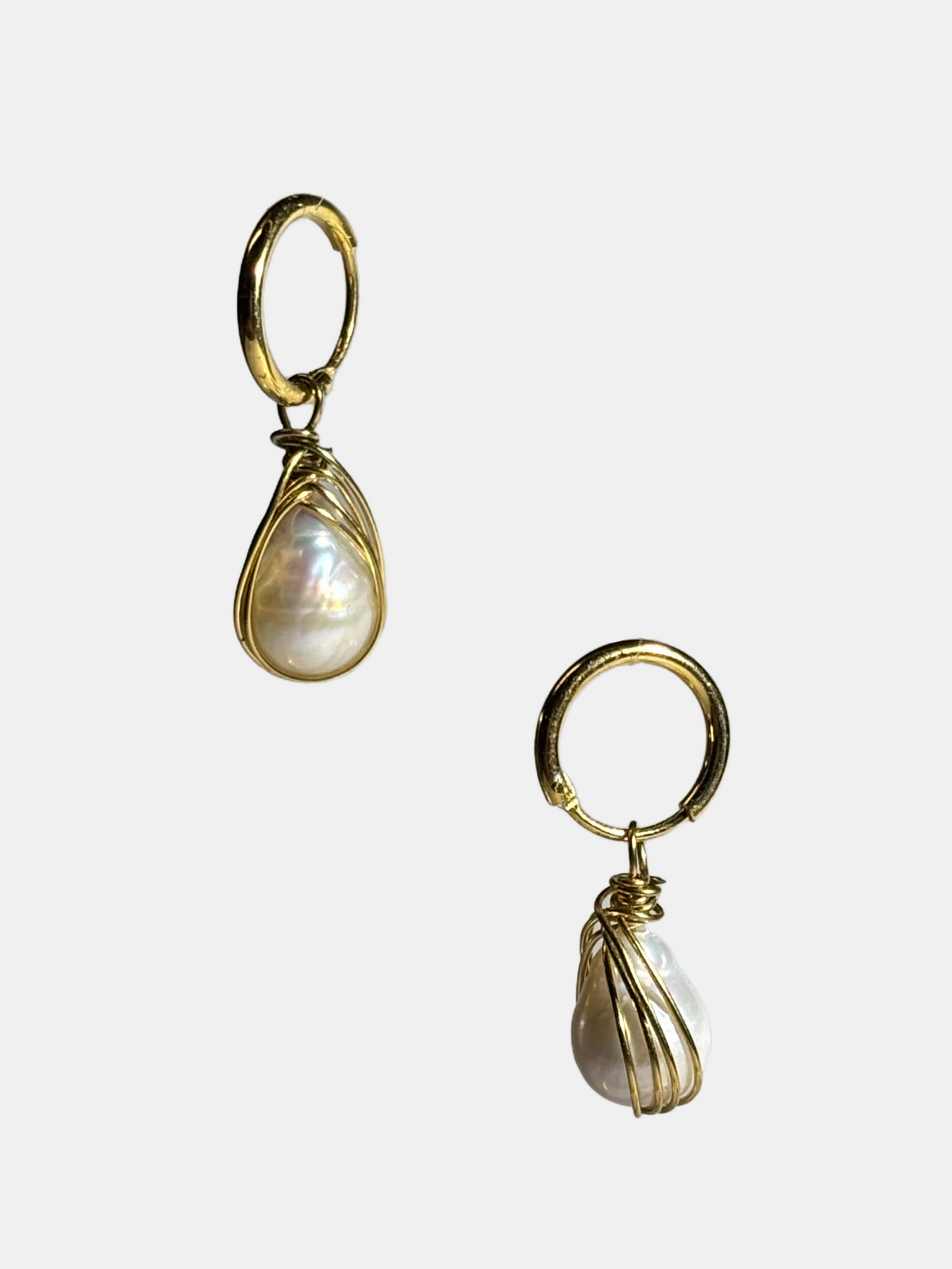 A pair of delicate gold wire-wrapped teardrop pearl earrings displayed against a white background.
