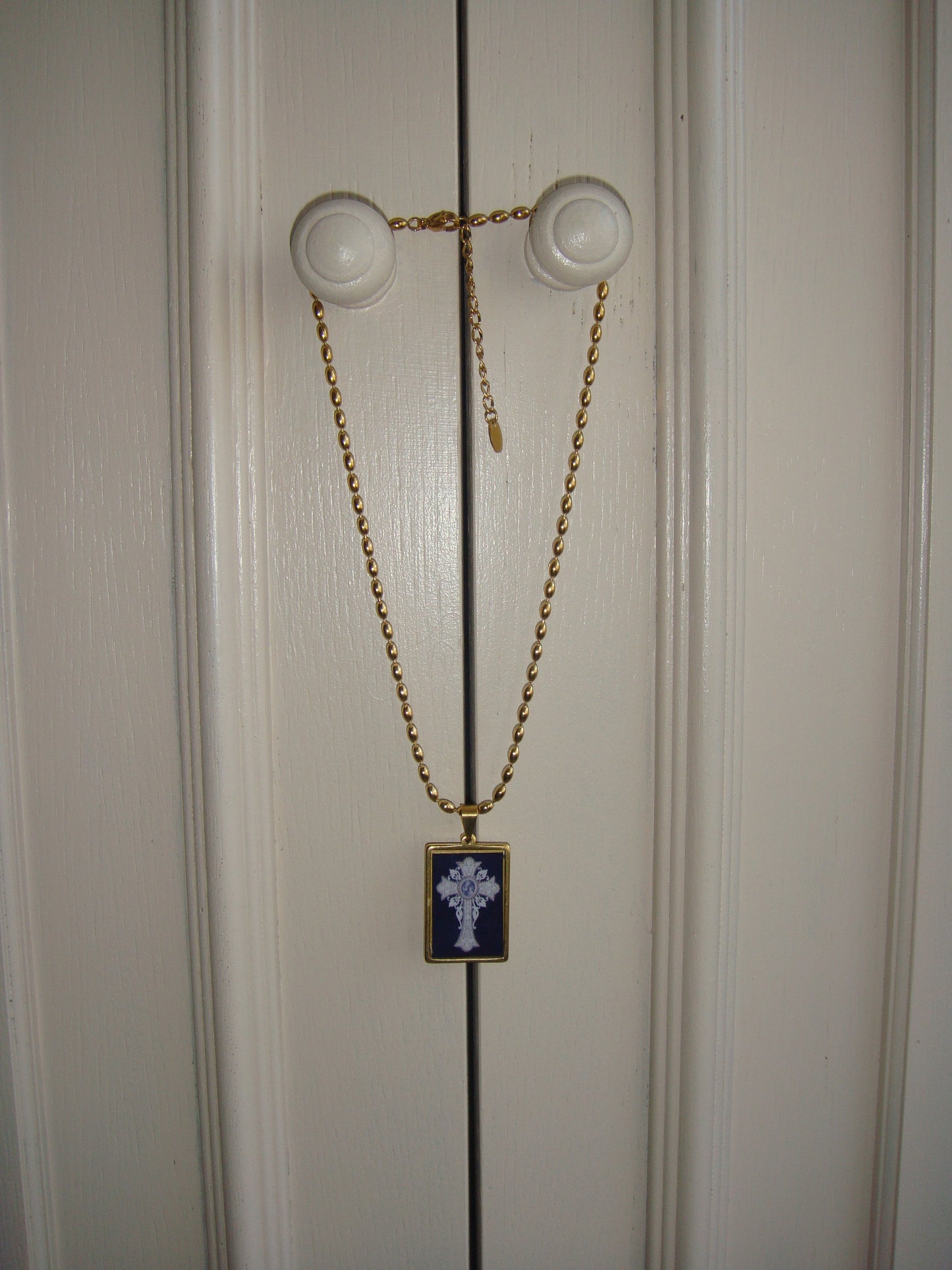 Unique handmade necklace with a gold chain and a glass-like black pendant featuring an intricate cross.