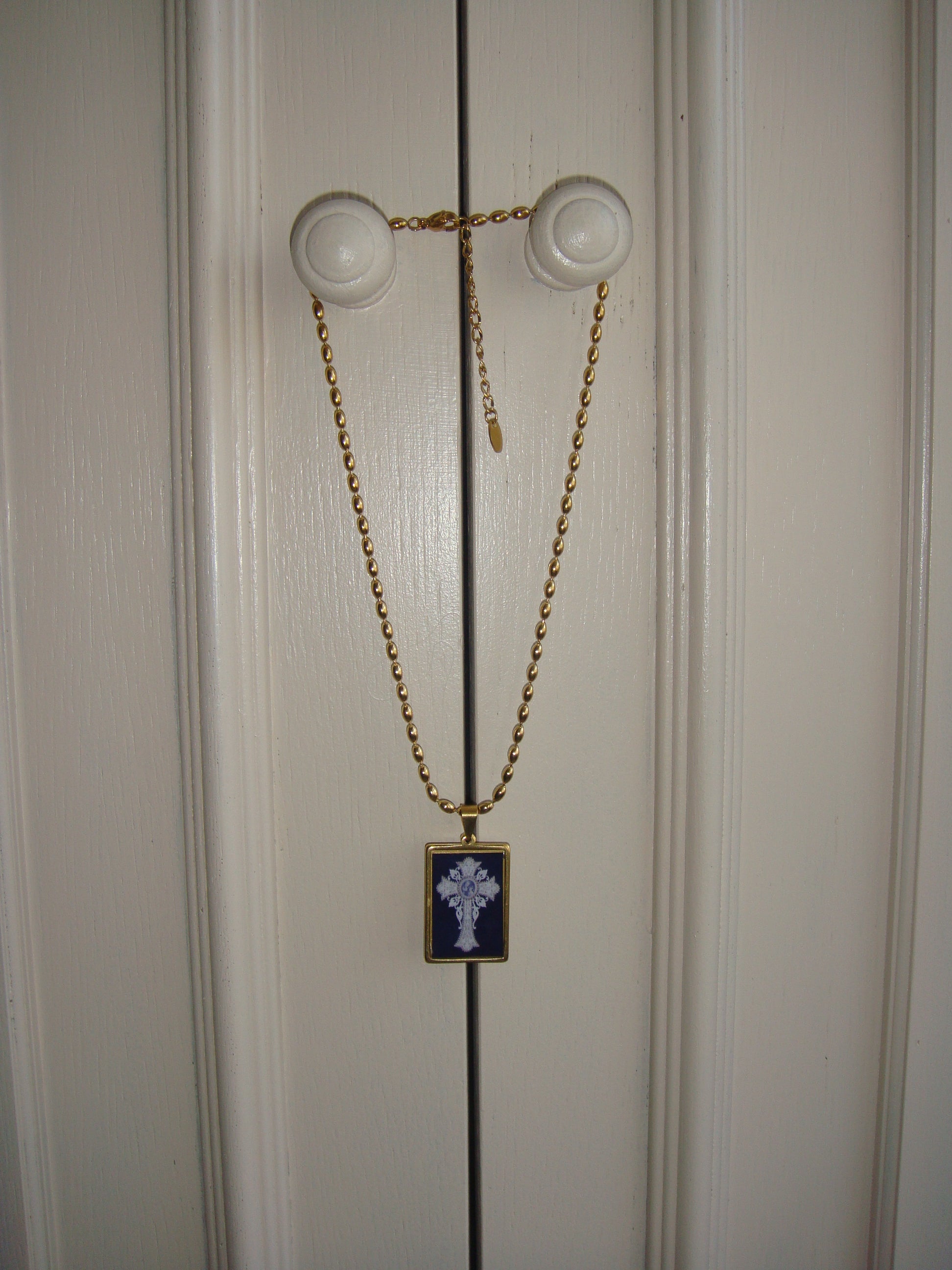 Unique handmade necklace with a gold chain and a glass-like black pendant featuring an intricate cross.