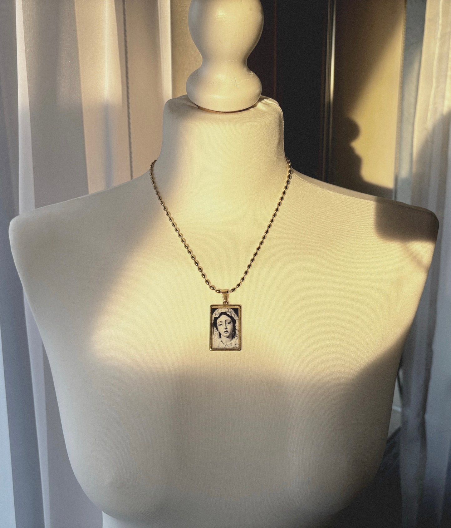 Rectangular gold necklace with black and white Mater Dolorum illustration