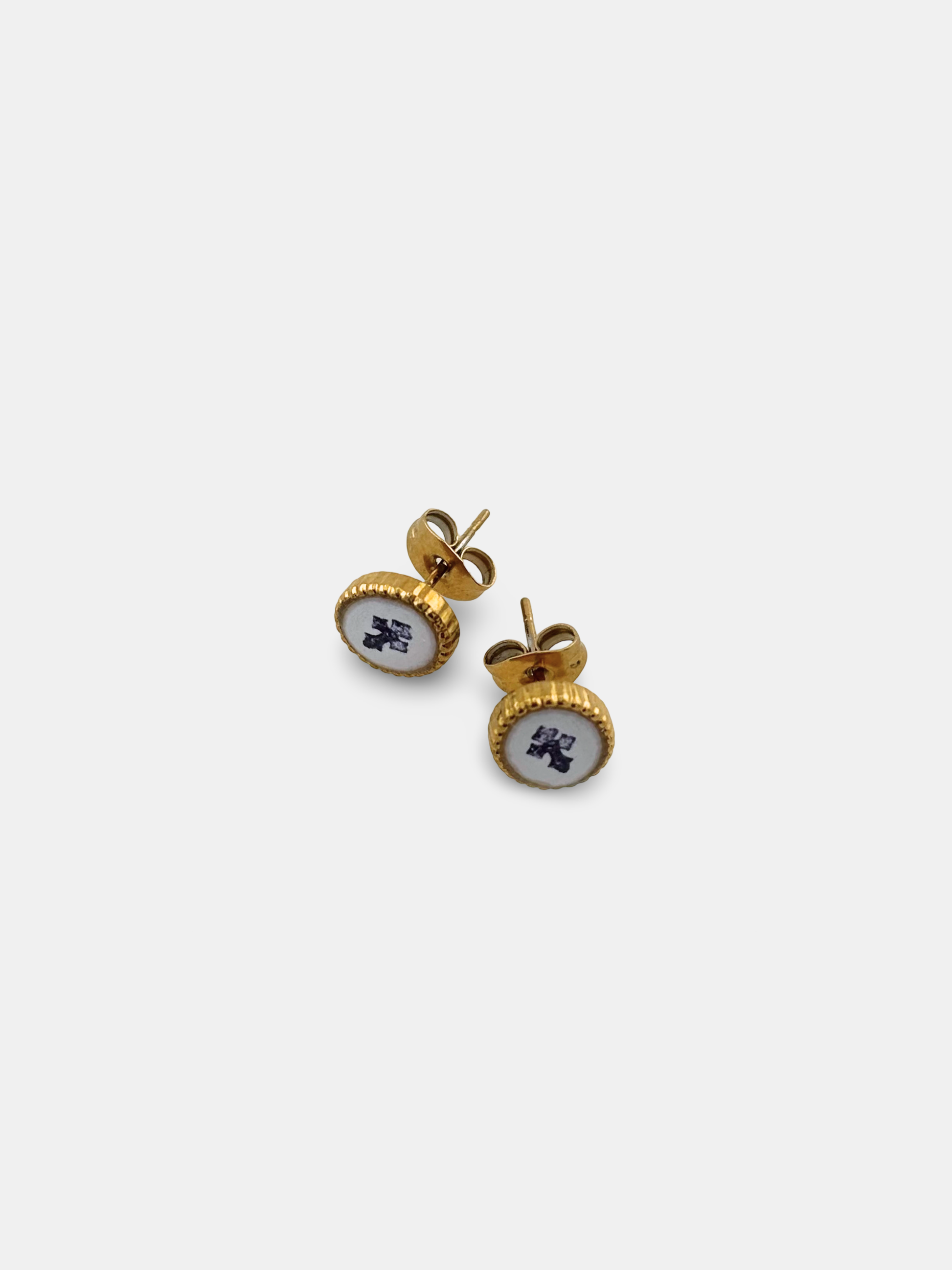 Oval gold stud earrings featuring a hand-painted cross beneath a glass-like dome.