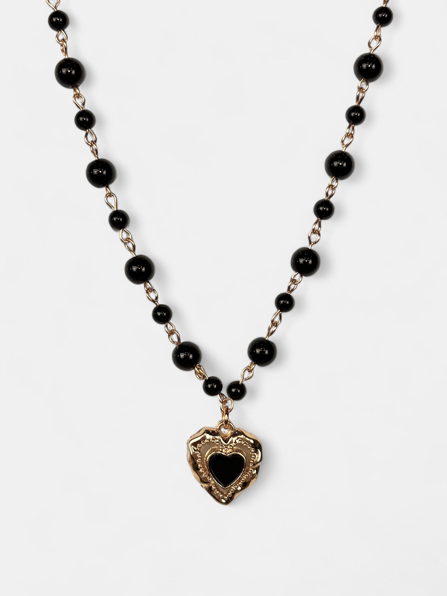 Vintage-inspired gold-plated heart pendant with black enamel detail, hanging from a black onyx bead choker.
