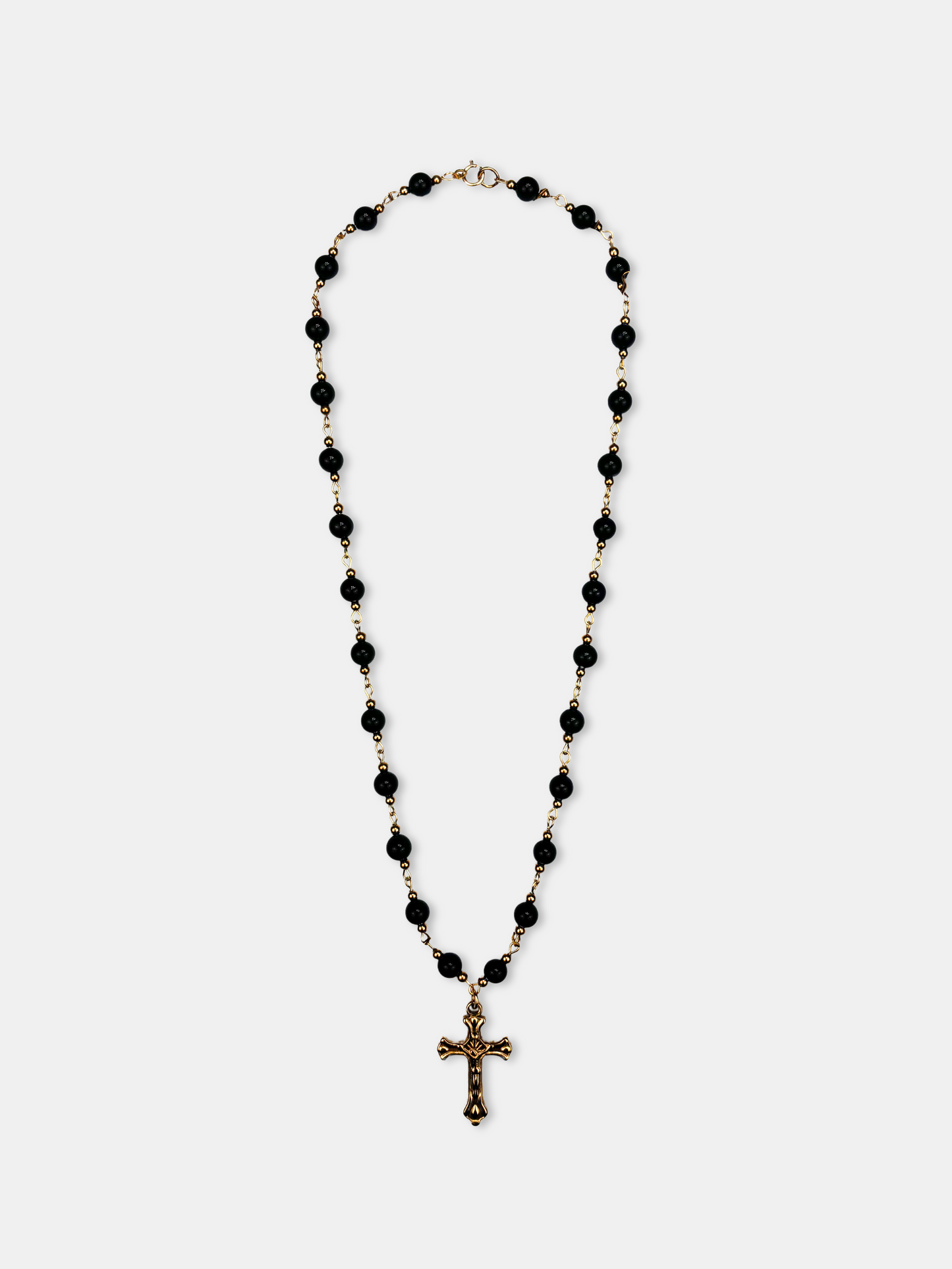 Gothic black onyx bead necklace with a gold cross pendant, inspired by vintage rosary-style jewelry.