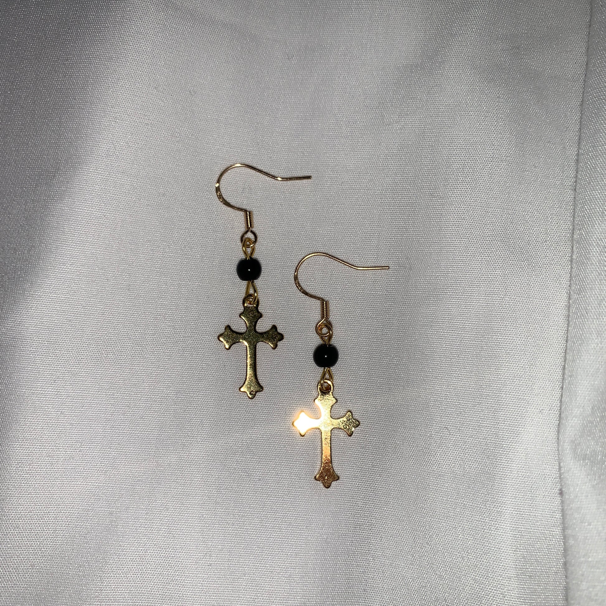 Handcrafted gold and black beaded cross earrings, blending classic symbolism with modern sophistication.