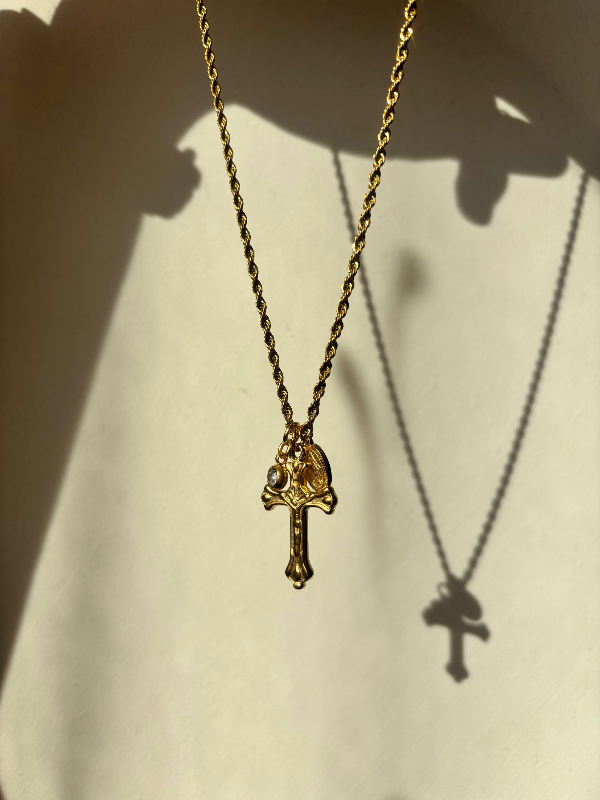 Faith-inspired gold cross charm necklace with a rope chain, religious pendants, and a minimalist gemstone accent – a stylish take on devotional jewelry.