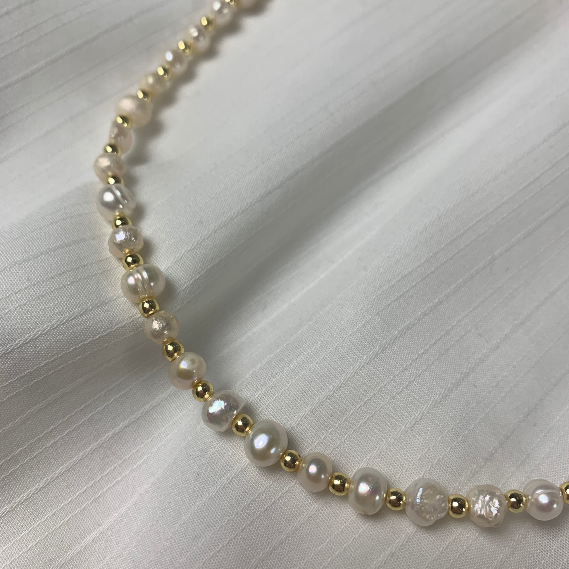 Delicate pearl choker with unique, organic-shaped freshwater pearls and gold accents for a timeless, artisanal touch.