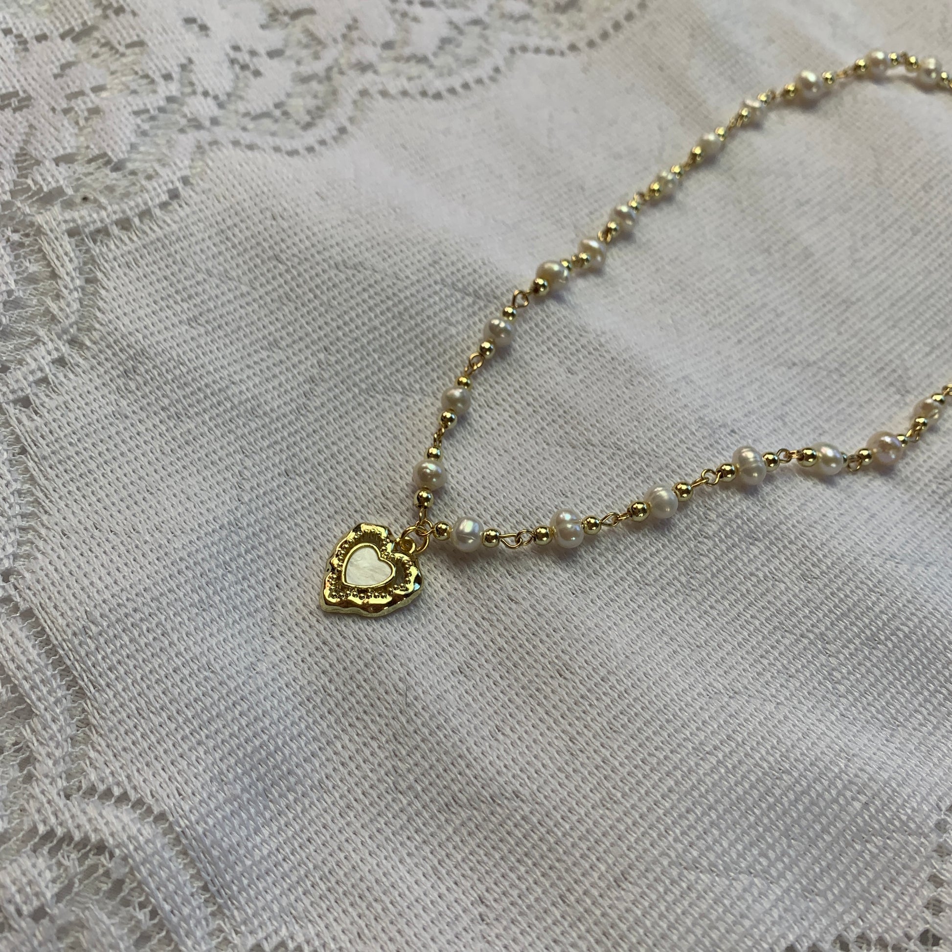 Aesthetic feminine pearl necklace with a gold heart charm, featuring delicate baroque pearls.