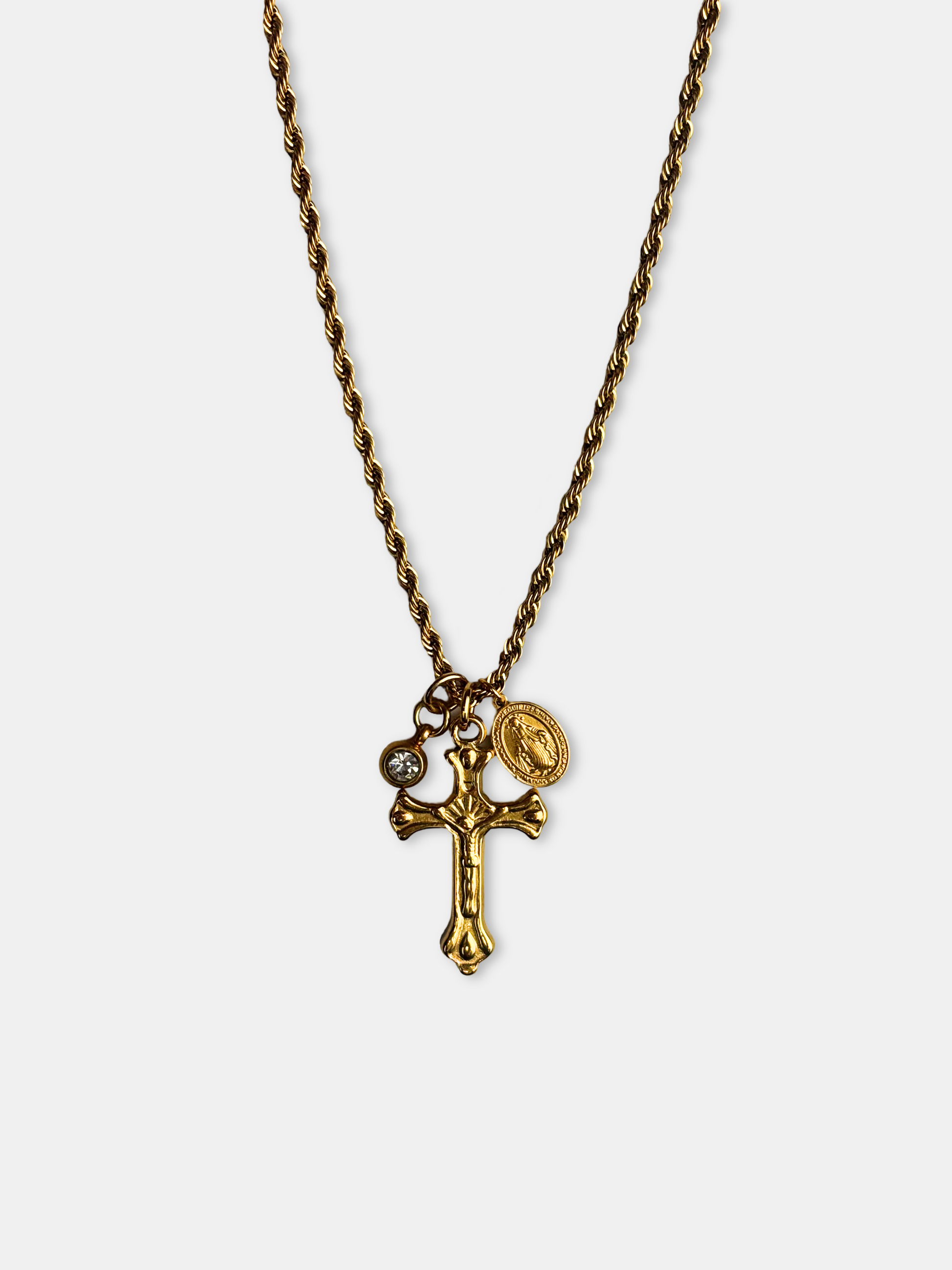 Gold vintage-style cross pendant necklace with a delicate rope chain, featuring a dainty crucifix charm, a Miraculous Medal, and a small crystal charm.