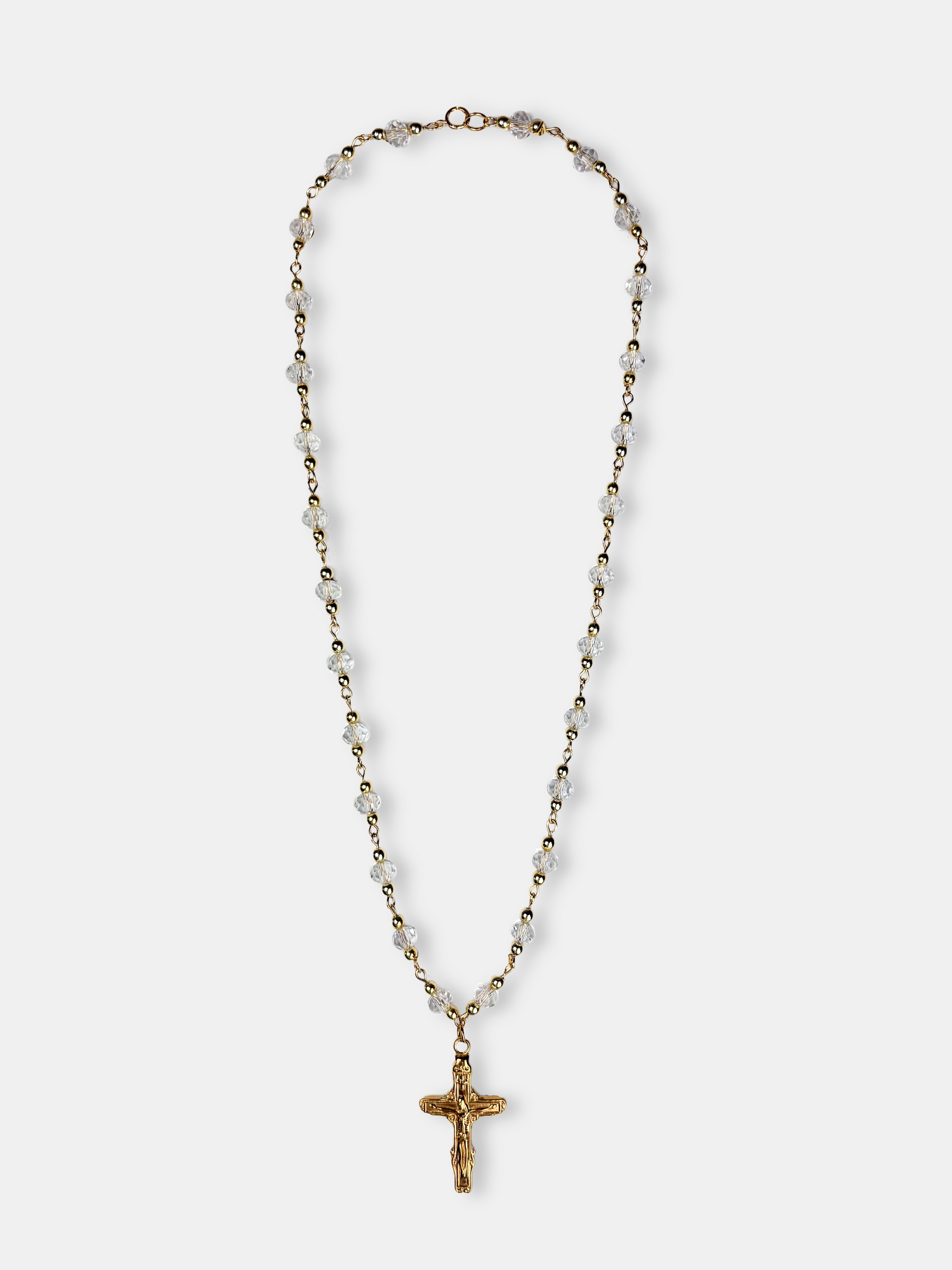 Gold rosary-style necklace with clear faceted beads and a detailed cross pendant, blending sophistication with classic design.