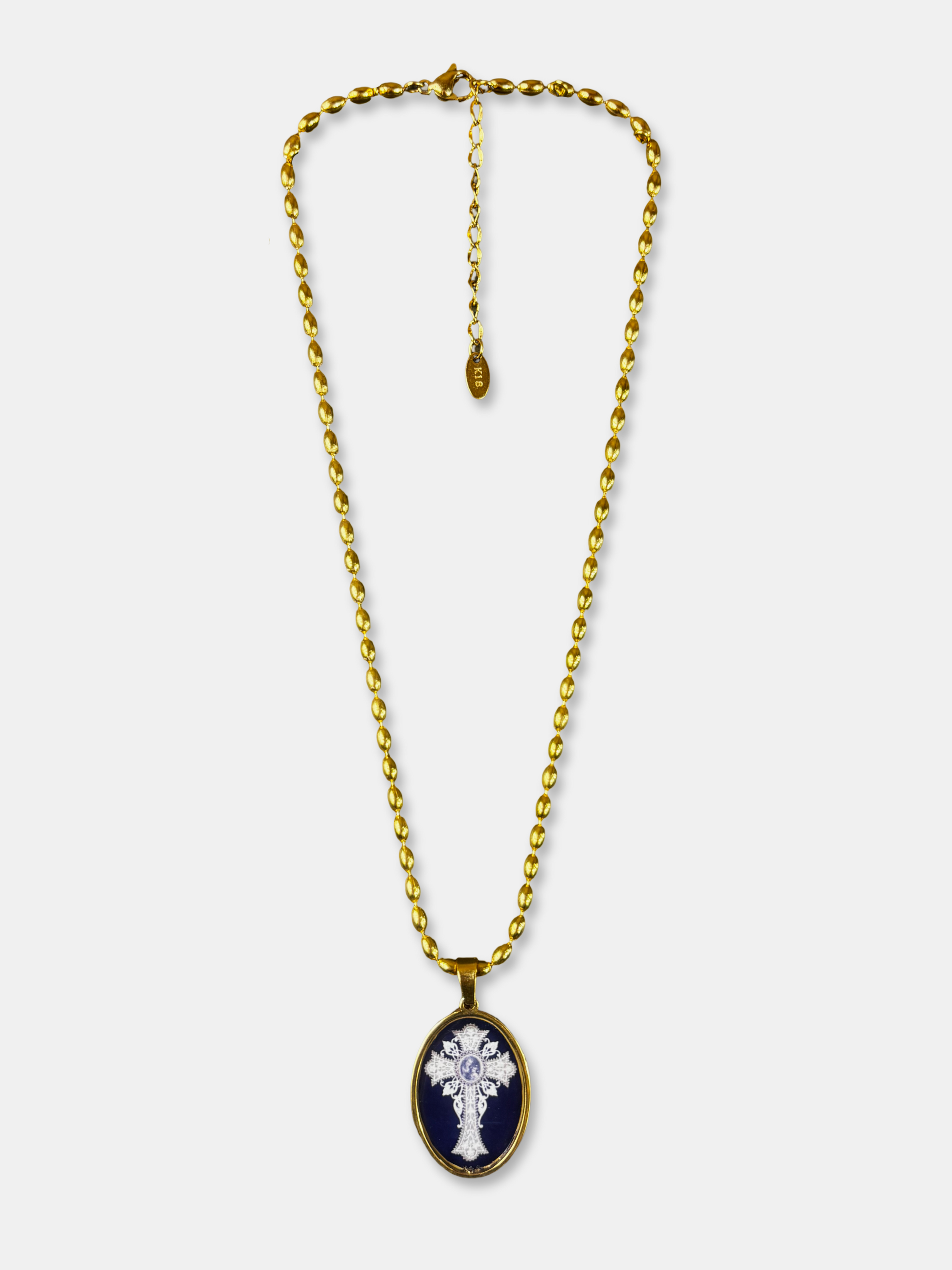 Oval cross pendant necklace with gold-filled chain and black enamel background.