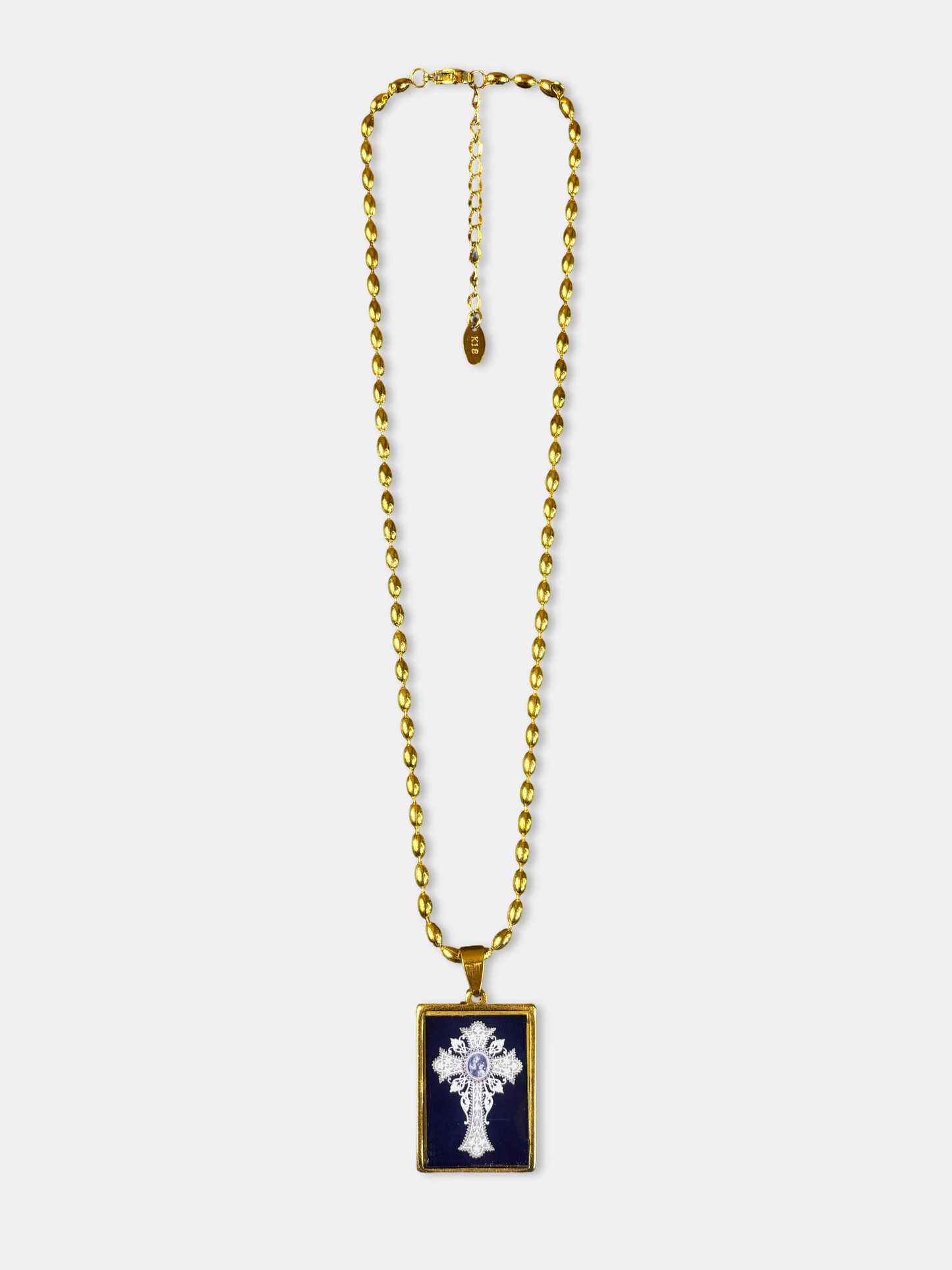 Gold-filled necklace with a vintage-style cross illustration beneath a glossy, glass-like dome.