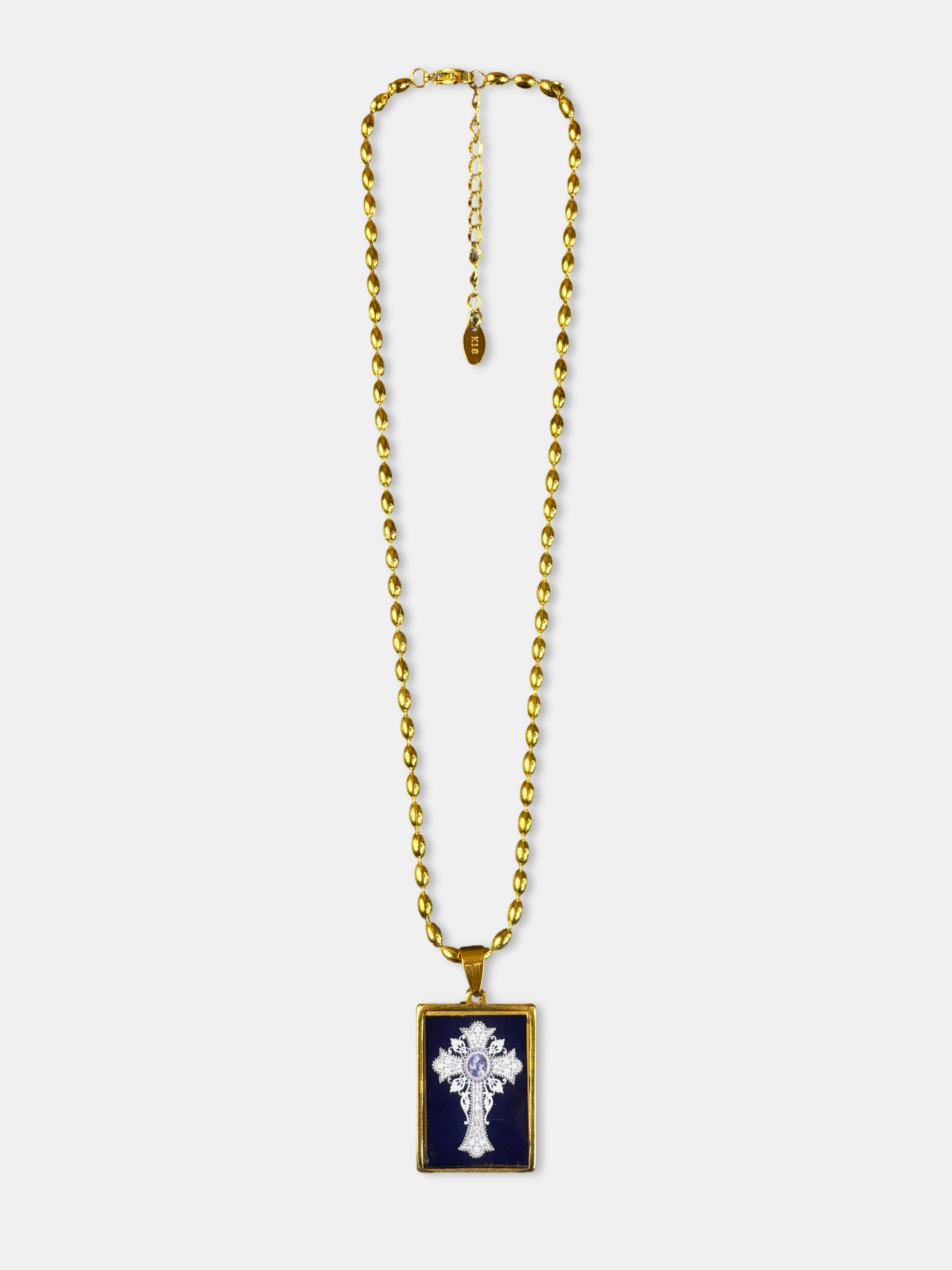 Gold-filled necklace with a vintage-style cross illustration beneath a glossy, glass-like dome.