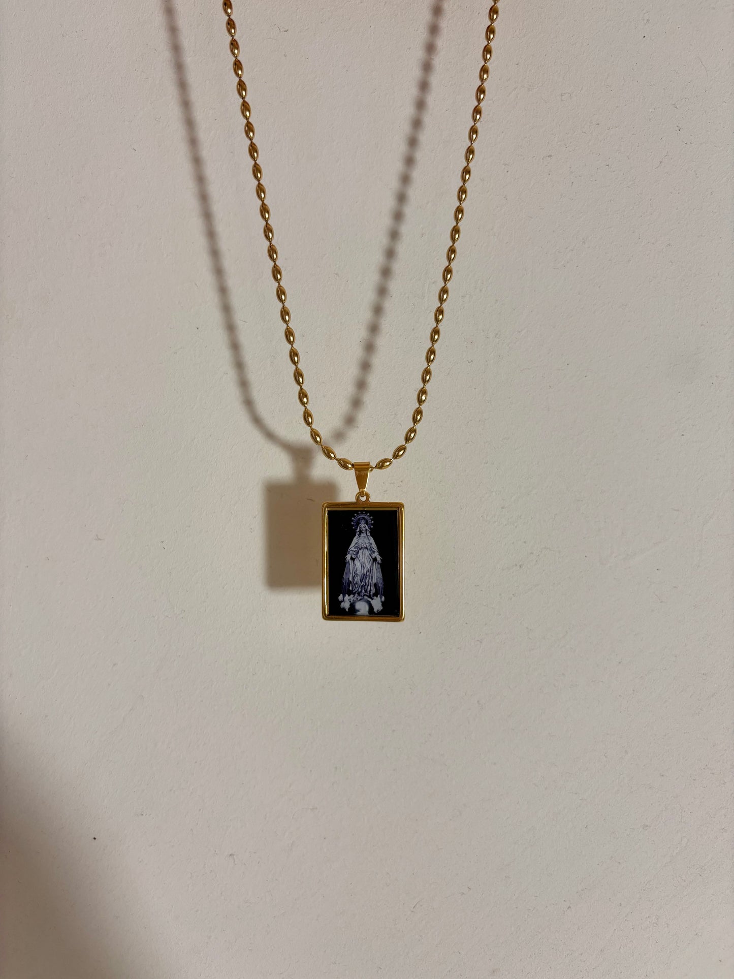 Gold-filled chain with rectangular black pendant showcasing a delicate Virgin Mary illustration.