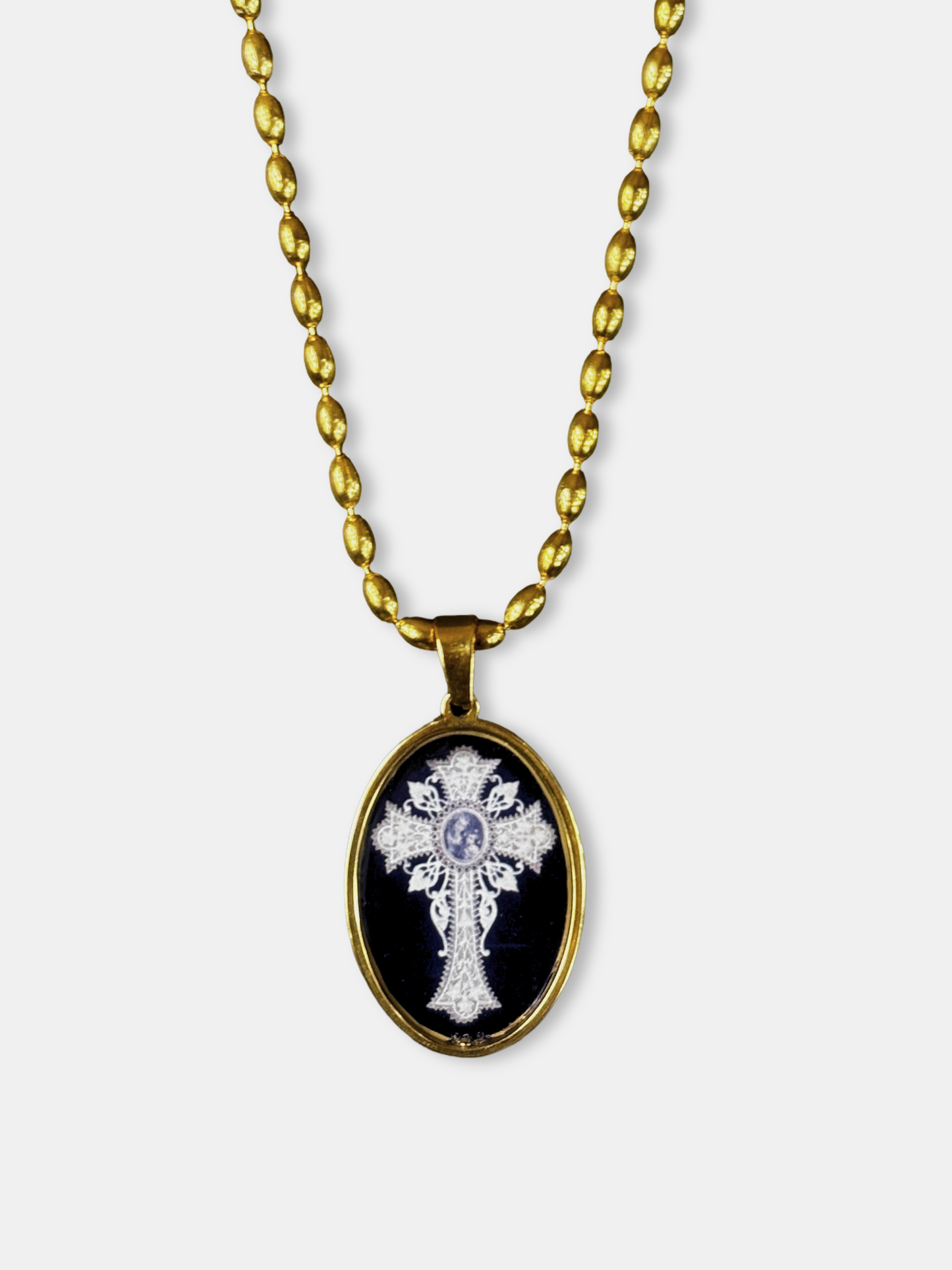 Vintage-inspired oval pendant necklace showing a white cross on deep black, crafted by an emerging designer.