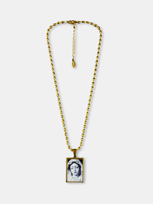 Gold necklace with rectangular pendant featuring sorrowful female portrait