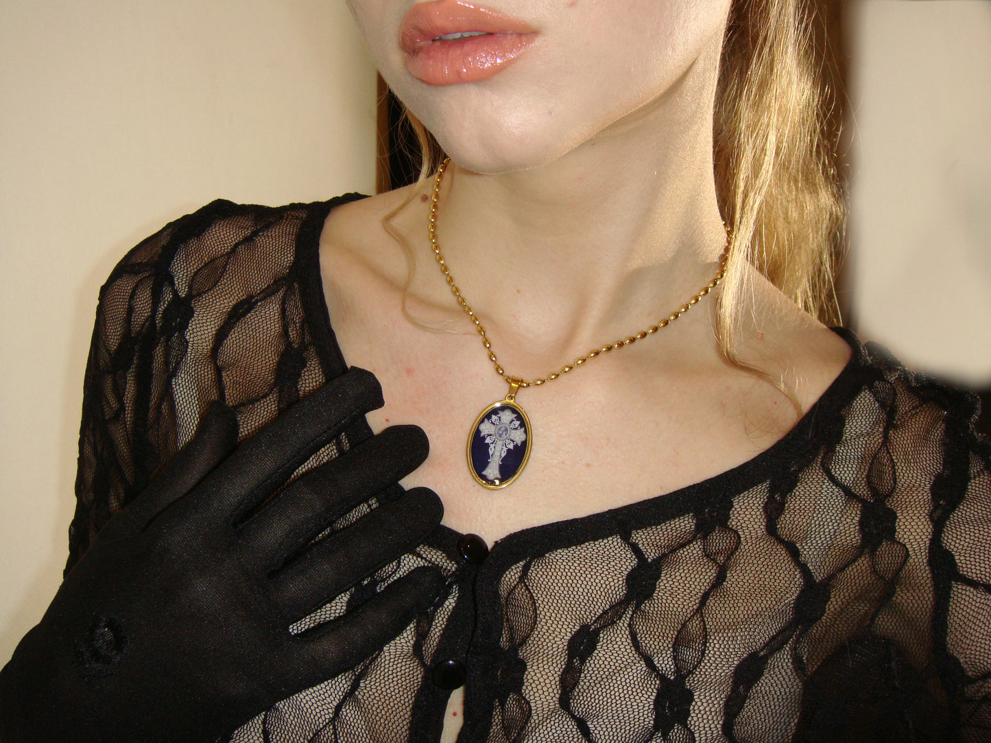 Oval black and gold cross necklace with glossy finish, reflecting sacred art influences.