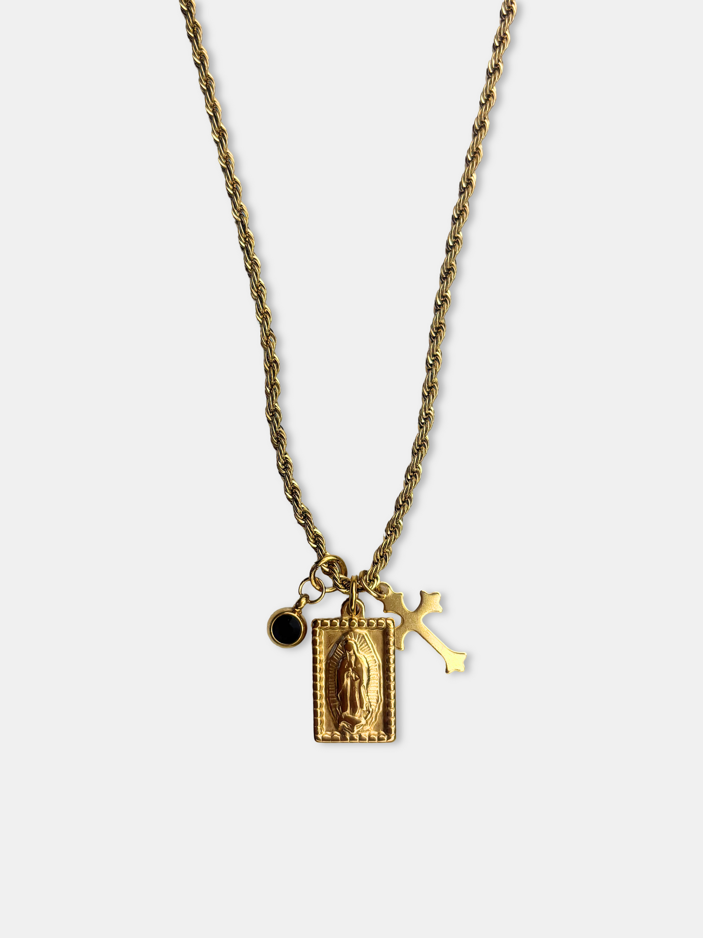 Gold Virgin Mary and cross charm necklace on a vintage-inspired rope chain, featuring a rectangular Our Lady of Guadalupe medal and a black gemstone accent.