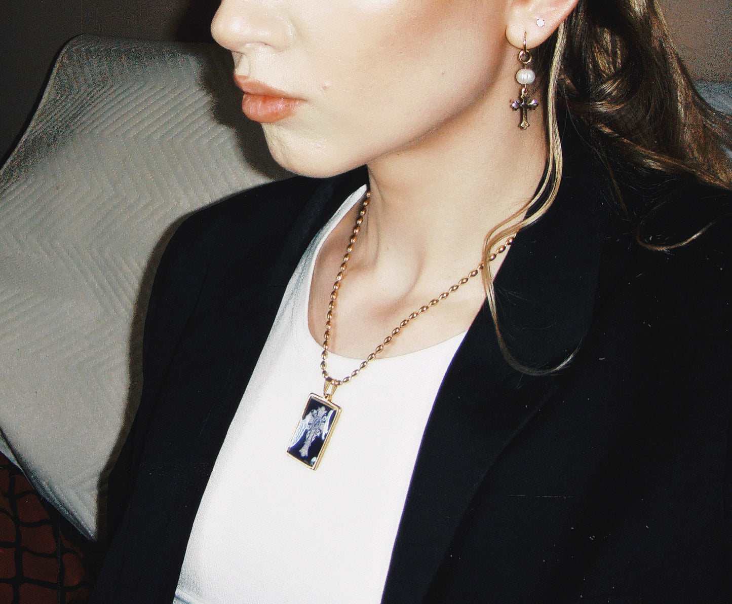 Handmade gold necklace featuring a black rectangular pendant with a detailed white cross design.