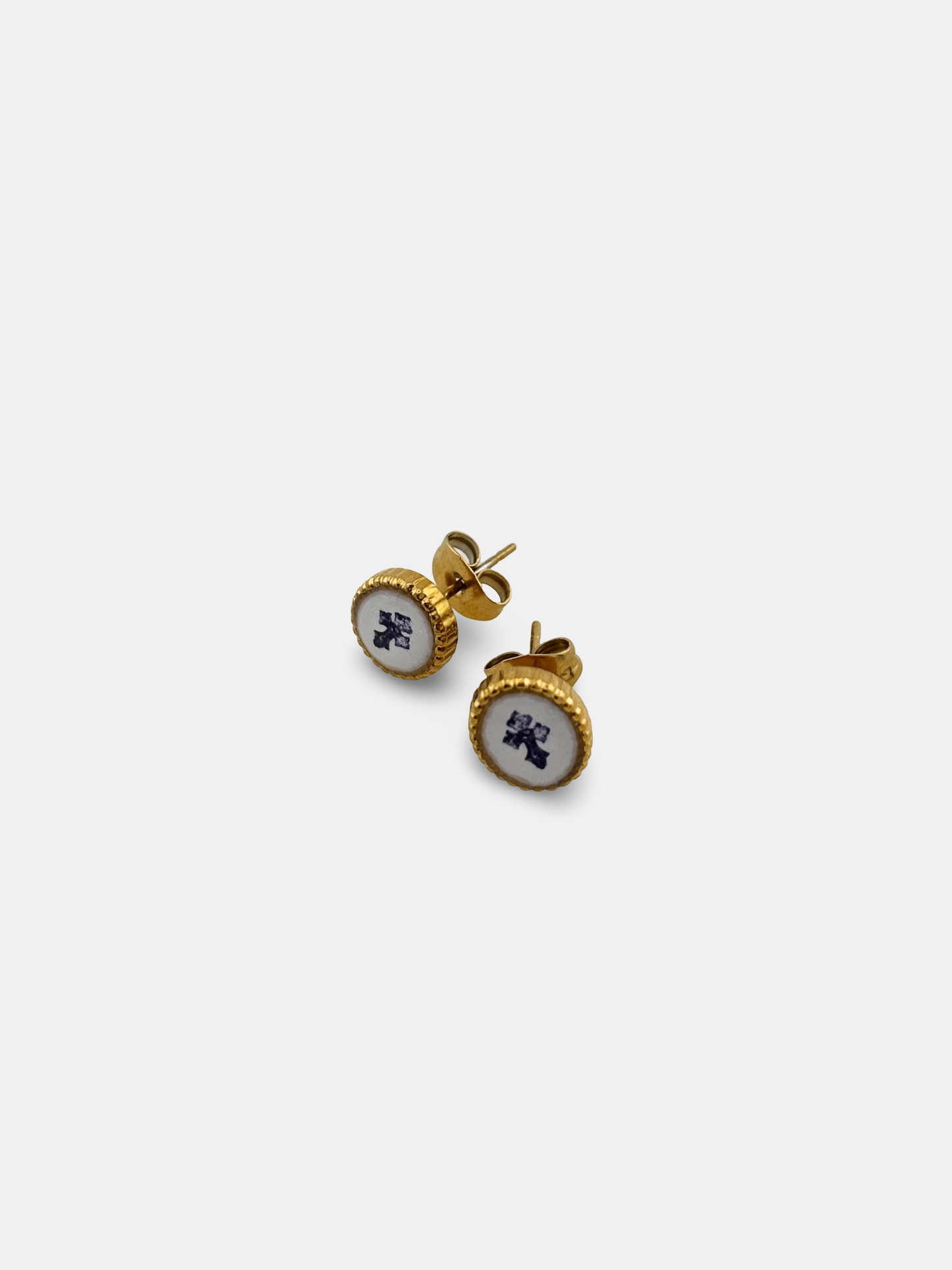 Oval cabochon earrings depicting a subtle cross motif under a glass-like surface.