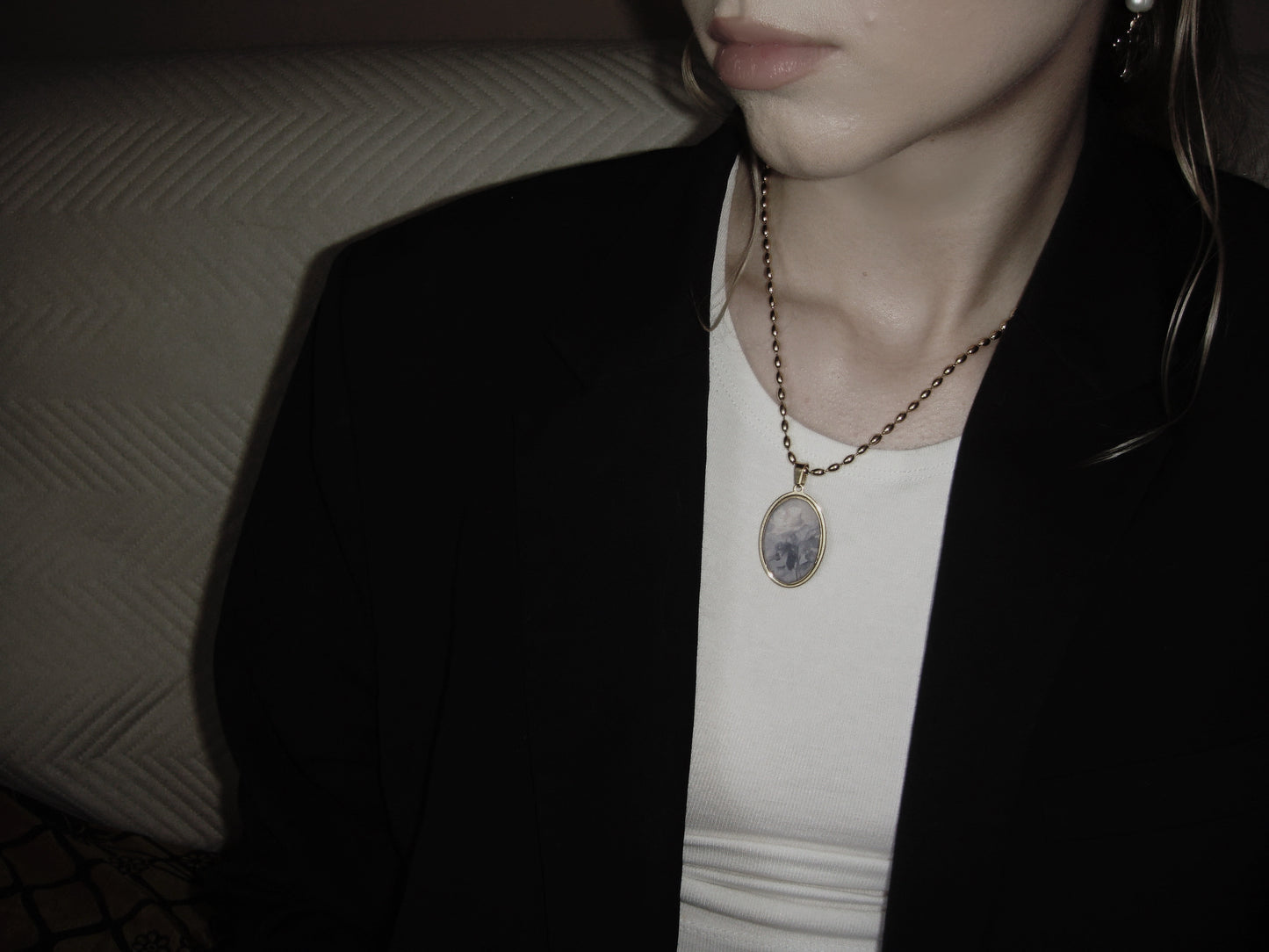 Dark romantic gold necklace with oval pendant, featuring a faded rose artwork on white background.