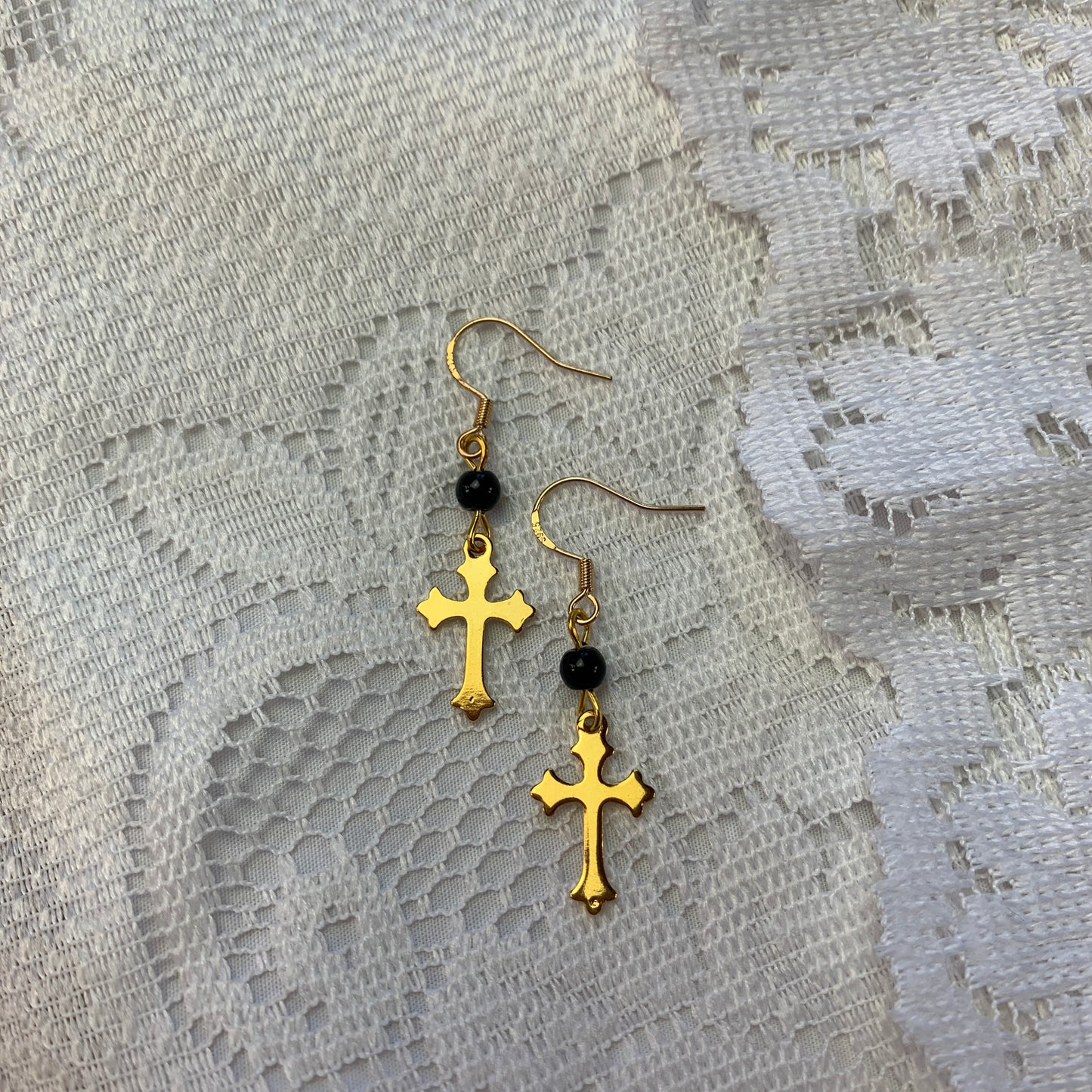 Gold cross dangle earrings with black onyx beads, gothic-inspired jewelry with dark feminine aesthetics.