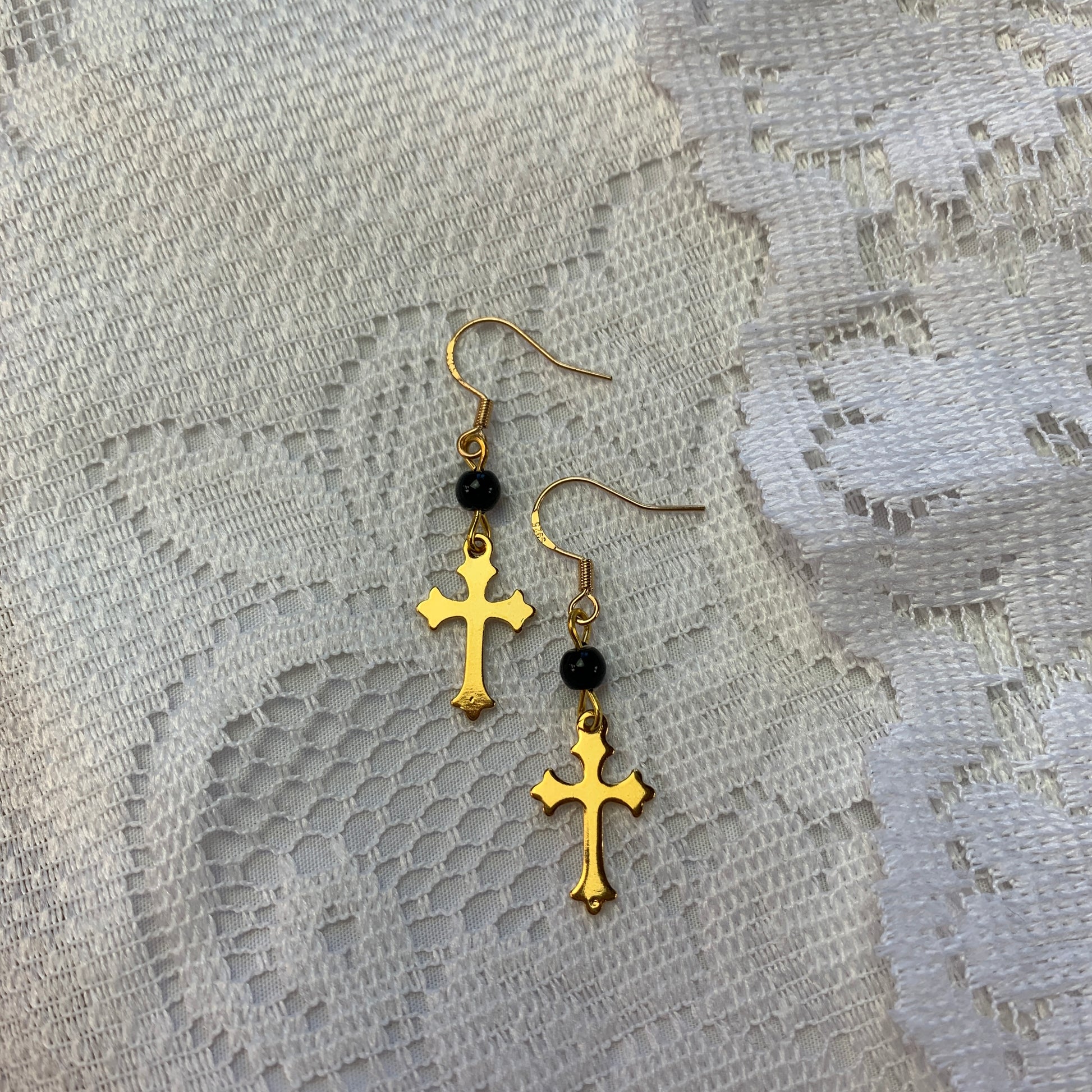 Gold cross dangle earrings with black onyx beads, gothic-inspired jewelry with dark feminine aesthetics.